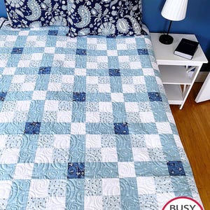 Peut inclure: Une courtepointe en patchwork bleu et blanc avec un motif de piqûre en spirale. La courtepointe est sur un lit avec deux oreillers à motifs paisley bleu et blanc. La courtepointe est fabriquée par Busy Hands Quilts, acheter fait main.