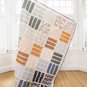 May include: A patchwork quilt with a geometric pattern in shades of blue, green, brown, and white. The quilt is made of different fabrics with floral and geometric prints.