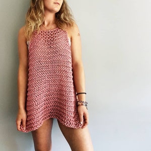 May include: A pink crocheted sleeveless top with a loose fit and a slightly uneven hemline.