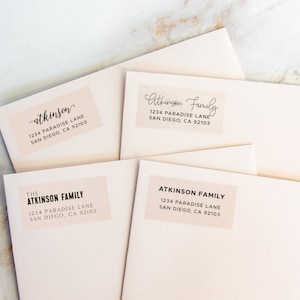 Peut inclure: Enveloppes rose pâle avec des étiquettes d'adresse. Les étiquettes indiquent le nom "Atkinson" ou "Atkinson Family" en écriture élégante et en lettres bâtons, ainsi que l'adresse : 1234 Paradise Lane, San Diego, CA 92103.