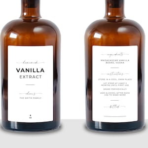 May include: Two amber glass bottles with white labels. The left label reads Homemade Vanilla Extract, Cheers, The Smith Family, 8 oz. The right label lists ingredients as Madagascar Vanilla Beans, Vodka, and instructions to store in a cool, dark place.