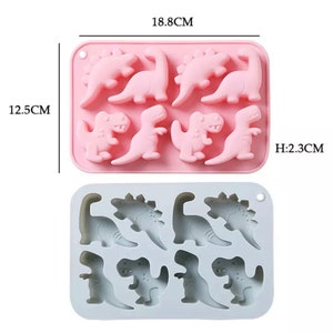 Könnte beinhalten: Rosa Silikon-Eiswürfelform mit 8 Vertiefungen in Dinosaurierform. Die Form ist 18,8 cm breit, 12,5 cm hoch und 2,3 cm tief.
