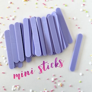 May include: A pile of lavender colored mini sticks, arranged in a fan shape, with the text "mini sticks" written in pink and purple lettering on a white background.