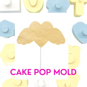 May include: A set of yellow and blue cake pop molds in various shapes, including a heart with wings, a house, a cloud, a number one, and a number zero. The molds are made of plastic and have a smooth surface. The text "CAKE POP MOLD" is printed in pink letters on the bottom of the image.