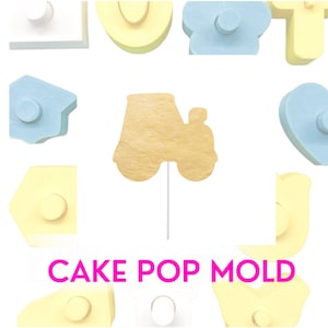 Puede incluir: Un molde para cake pops amarillo con forma de tractor. El molde es de plástico y tiene un palo pegado en la parte inferior. El molde está rodeado de otros moldes para cake pops de diferentes formas y colores. El texto "CAKE POP MOLD" está impreso en letras rosas debajo del molde.