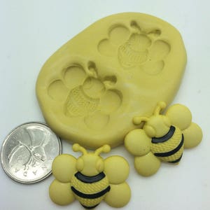 以下が含まれることがあります： 蜂の形をした装飾を作るための、黄色のシリコンモールドが2つ。黄色の蜂の形をした装飾が2つも写っています。