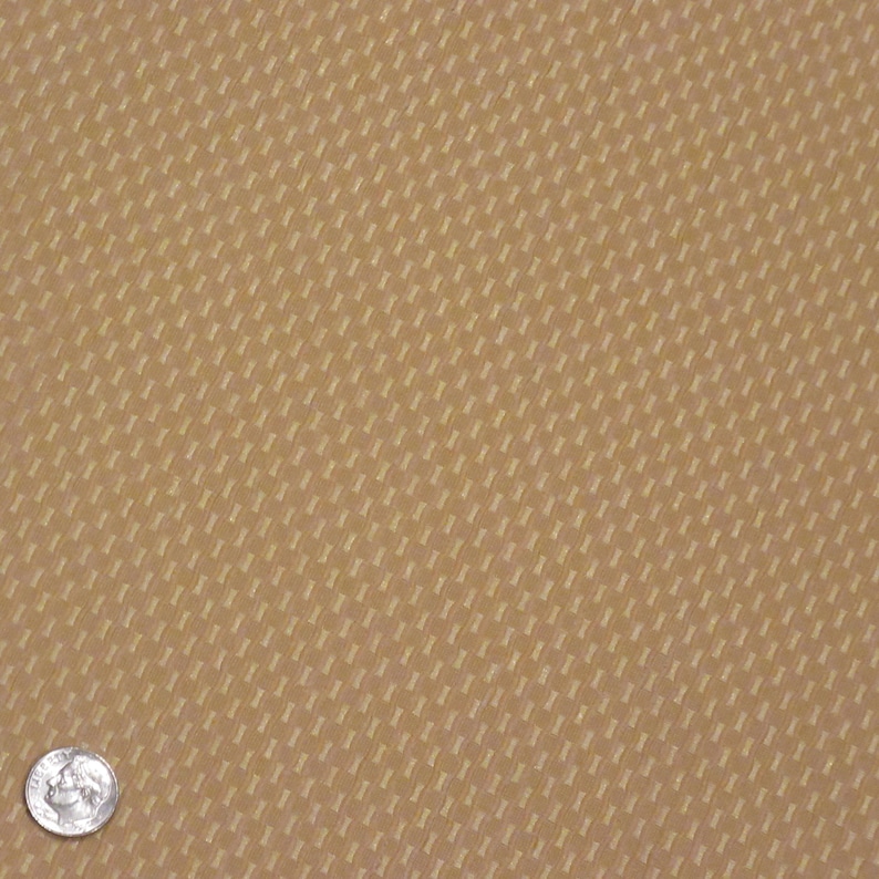 May include: Close-up of a tan fabric with a repeating pattern of small, rectangular shapes. The texture appears slightly raised, creating a subtle visual depth. A US quarter coin is in the lower left corner for scale.
