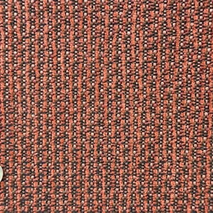 May include: Close-up of a textured fabric with a repeating pattern of vertical lines. The fabric is primarily orange-red with black and white flecks, creating a woven appearance. A quarter coin is in the lower left corner.