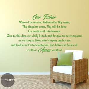 May include: A green wall sticker displaying the Lord's Prayer in a script font. The text is applied to a light yellow wall. A wicker chair with a white cushion and a green cushion is in the foreground.