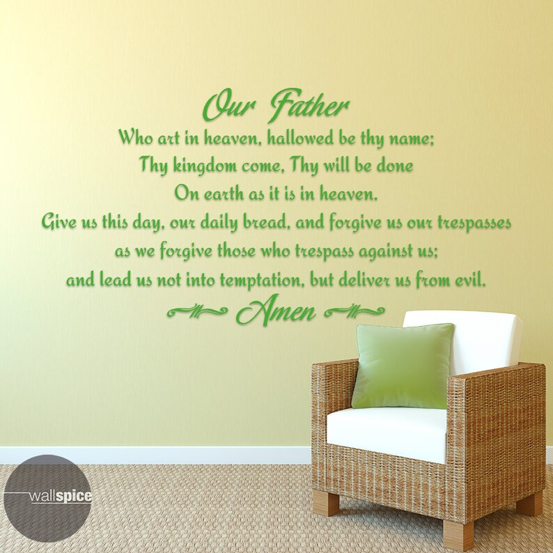 May include: A green wall sticker displaying the Lord's Prayer in a script font. The text is applied to a light yellow wall. A wicker chair with a white cushion and a green cushion is in the foreground.
