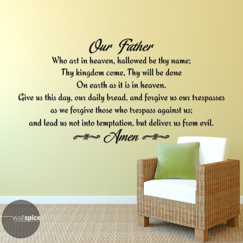 May include: A wall decal displaying the Lord's Prayer in black script on a pale yellow wall. A wicker armchair with a white cushion and a green pillow is positioned in the image.