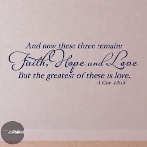 Può includere: Un adesivo da parete con un carattere corsivo blu navy che recita "And now these three remain: Faith, Hope and Love. But the greatest of these is love. -1 Cor. 13:13"
