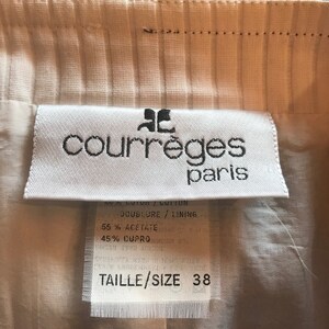 May include: White clothing label with black text that reads "courr&egrave;ges paris". The label also includes the text "DOUBLURE / LINING", "55% ACETATE", "45% CUPRO", and "TAILLE/SIZE 38".