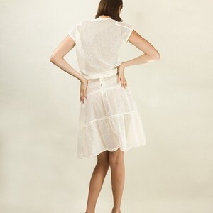 May include: A white crochet dress with a fitted bodice and a tiered skirt. The dress is made of a lightweight, breathable fabric and has a delicate, feminine look.