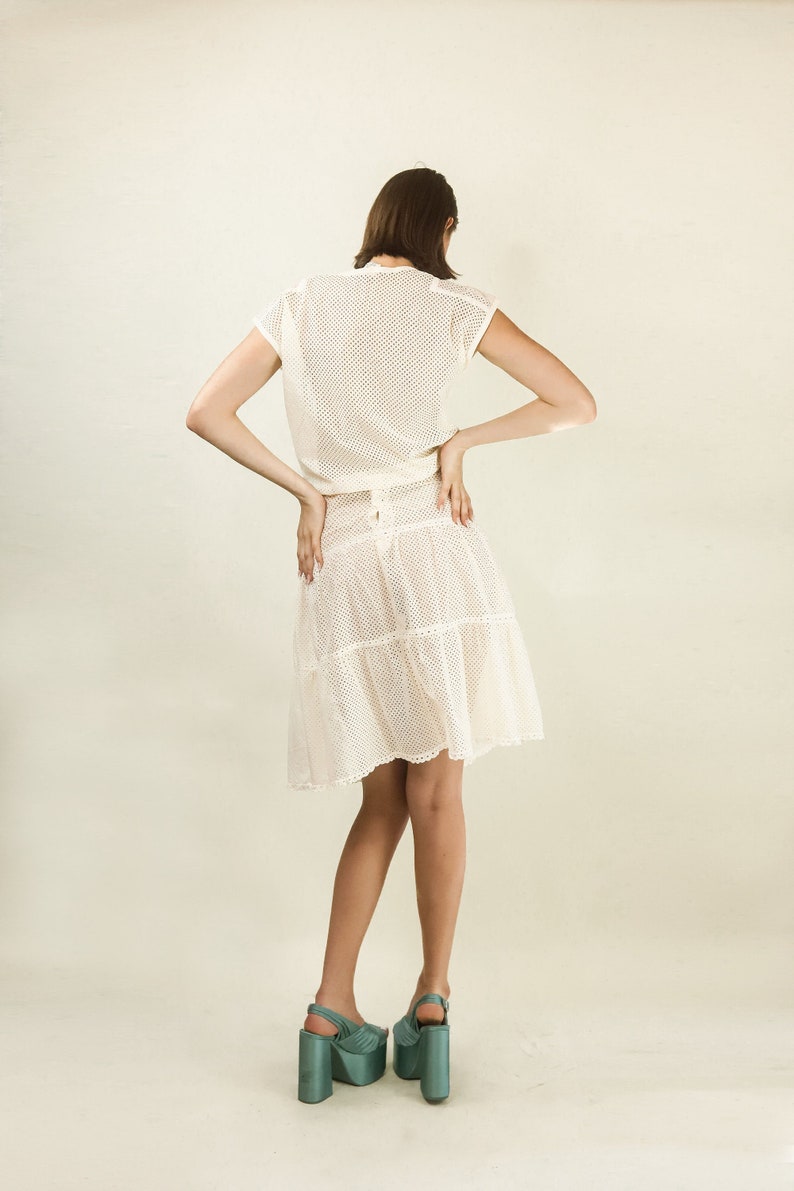 May include: A white crochet dress with a fitted bodice and a tiered skirt. The dress is made of a lightweight, breathable fabric and has a delicate, feminine look.