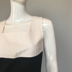 May include: A sleeveless dress with a white bodice and a black skirt. The bodice has horizontal stripes and a square neckline.