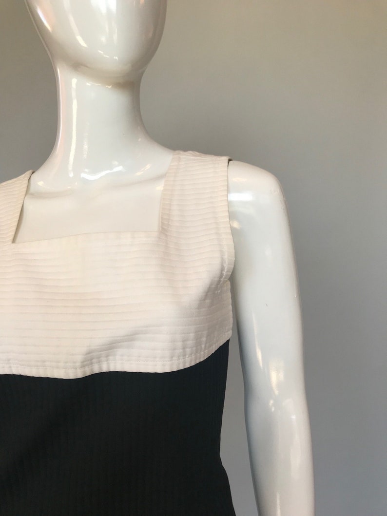 May include: A sleeveless dress with a white bodice and a black skirt. The bodice has horizontal stripes and a square neckline.