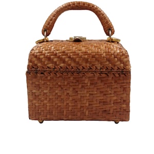 May include: A vintage brown woven handbag with a curved handle and a rectangular shape. The bag features a woven pattern, a clasp closure, and small gold-colored feet. The handle is attached with gold-colored hardware.