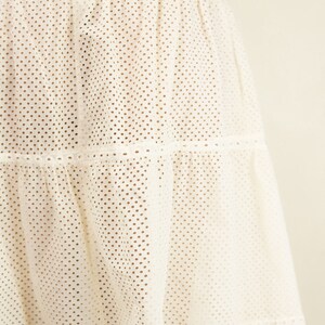 May include: A white tiered skirt with a dotted pattern and a scalloped hem.