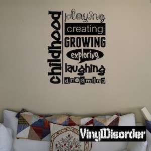 May include: Black and white vinyl wall decal with the words "childhood", "playing", "creating", "growing", "exploring", "laughing", and "dreaming" arranged vertically. The decal is on a light beige wall.