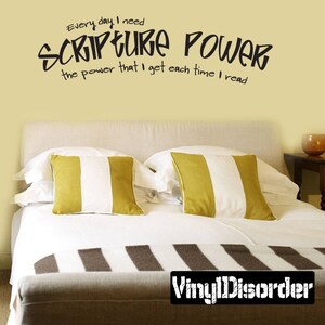 May include: A white bed with a brown and white striped blanket and two yellow and white striped pillows. The wall behind the bed is a light yellow color and has a black vinyl decal that reads "Every day I need SCRIPTURE POWER the power that I get each time I read".