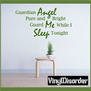 Puede incluir: Una pared blanca con texto verde que dice "Guardian Angel Pure and Bright Guard Me While I Sleep Tonight". Un pequeño árbol en maceta se encuentra sobre una mesa de madera frente a la pared.