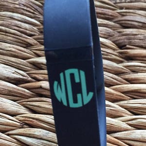 May include: A black silicone bracelet with a teal monogram that reads "WCL".