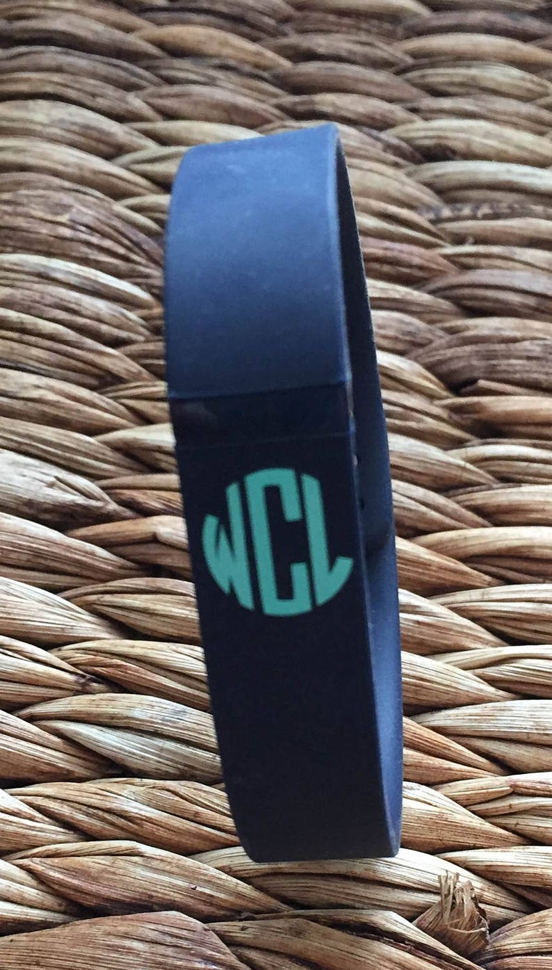 May include: A black silicone bracelet with a teal monogram that reads "WCL".