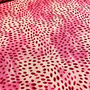 May include: Pink fabric with a white and pink swirl pattern and small, raised pink dots.