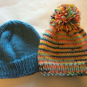 May include: Two knitted hats. One is solid blue, the other is striped with orange, teal, yellow, and navy blue. The striped hat has a large pom-pom on top made of matching yarn colors. Both hats are made of soft yarn.