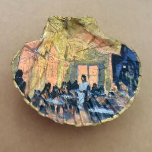 May include: Hand-painted seashell featuring a depiction of a gathering, possibly a restaurant or social event. The artwork uses a palette of warm yellows, oranges, and blues, with visible brushstrokes. The shell's edges are highlighted with gold paint, adding a decorative touch.