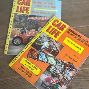May include: Two vintage "Car Life" magazines. One is dated July 1955, with a red sports car on the cover. The other, dated April 1955, features an orange cover with multiple cars and the text "1955 Auto Review".