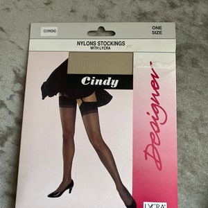 Puede incluir: Paquete de medias de nylon beige con la marca "Cindy Designer" y el texto "Nylon Stockings with Lycra" y "One Size" impreso en la parte delantera.