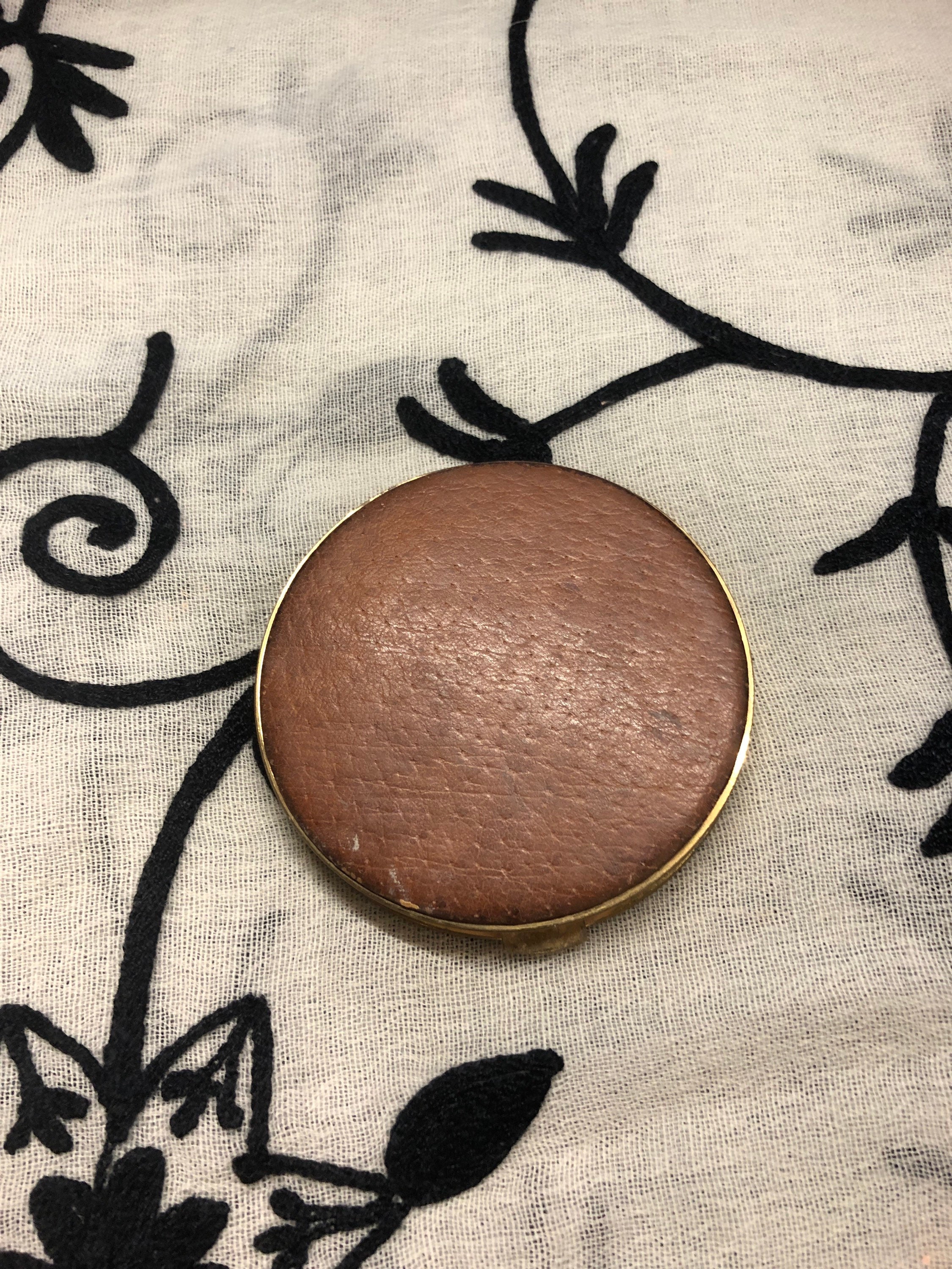 Original vintage gold effect circular powder compact with a tan leather top and decorative linen pattern on the base