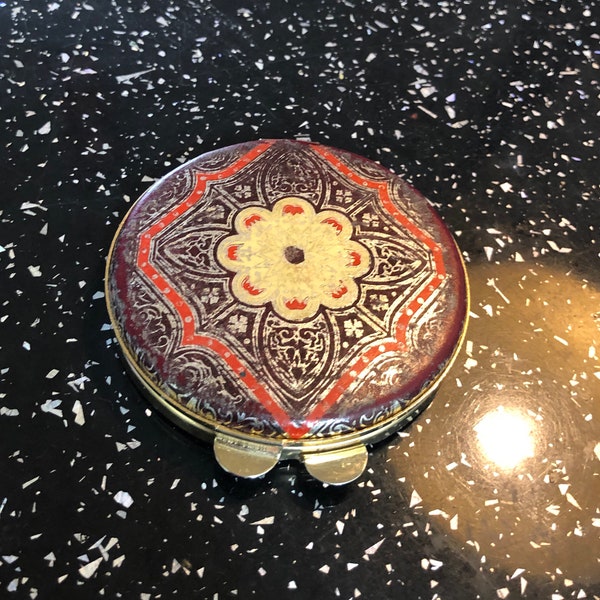 Original vintage gold effect circular powder compact with a burgundy leather top and base, decorated in an far eastern  pattern on the top