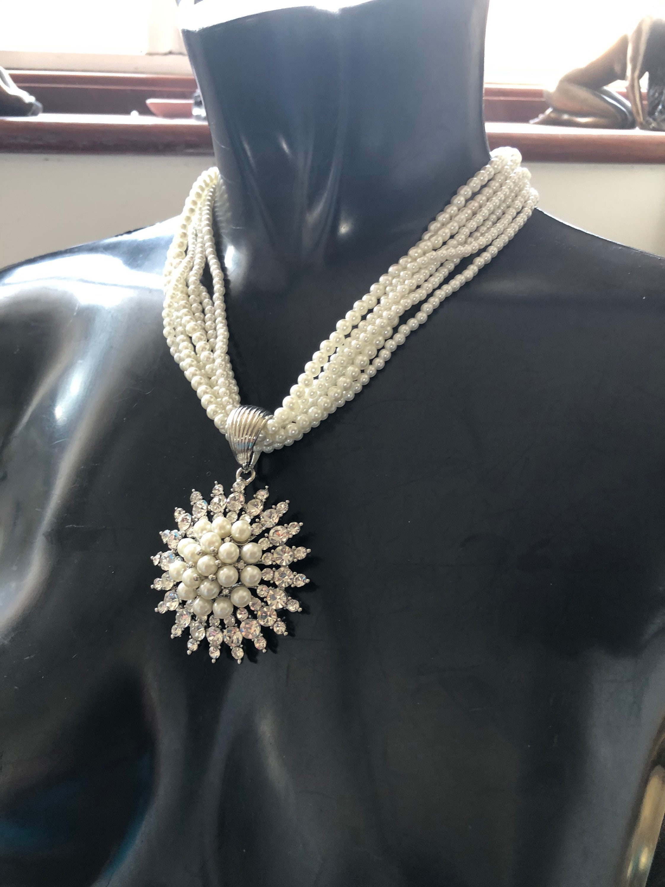 Such an unusual diamanté and pearl sunburst pendant hung on a 6 string faux pearl necklace.