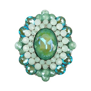 May include: A green and blue jeweled brooch with a large oval-shaped green stone in the center.
