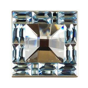 May include: A square-shaped crystal knob with a light blue colour and a silver frame. The crystal is faceted and has a reflective surface.