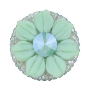 Op de afbeelding: Een lichtgroene bloem met een helder kristallen hart, omringd door een ring van heldere strasssteentjes.