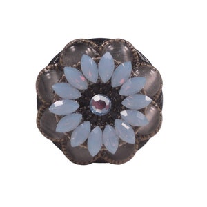 May include: A decorative floral-shaped knob with a light blue and gray color scheme. The knob has a central rhinestone and is surrounded by smaller rhinestones.
