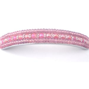 Op de afbeelding: Een roze haarspeld met kralen en een zilveren metalen basis. De kralen zijn in drie rijen gerangschikt, met in de middelste rij grotere, iriserende kralen.