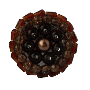 May include: A round, brown, beaded embellishment with a central pearl-like bead surrounded by smaller black beads.