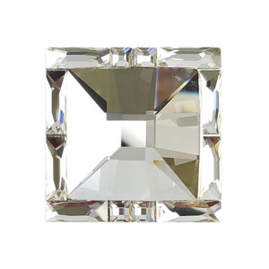 May include: A clear crystal square prism with a faceted design. The prism has a square shape and is made of clear glass.