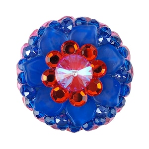 May include: A blue and pink flower-shaped bead with a red and clear crystal centre.