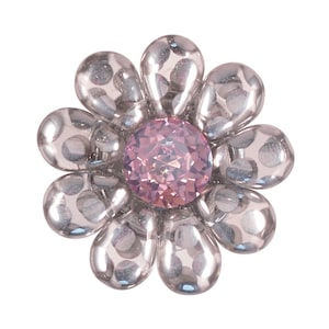 May include: A silver flower-shaped embellishment with a pink rhinestone in the center. The flower has a dotted pattern.