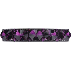 May include: A black barrette with a row of five purple rhinestones.