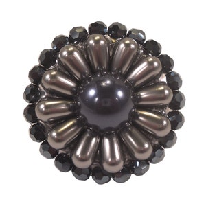 Könnte beinhalten: Eine schwarze und silberne Brosche in Blumenform mit einer großen schwarzen Perle in der Mitte. Die Brosche ist von kleineren schwarzen Perlen umgeben.