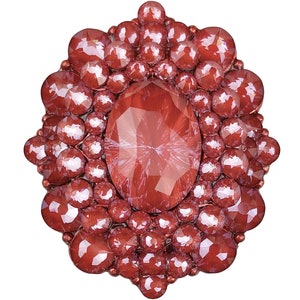 以下が含まれることがあります： 小さな赤いファセットカットの宝石で囲まれた、大きな赤いファセットカットの宝石。大きな宝石は楕円形で、小さな宝石は丸い。この作品はブローチまたはピンです。