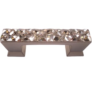 Könnte beinhalten: Ein silberner Schrankgriff mit rechteckiger Basis und einer mit Kristallen besetzten Oberseite.