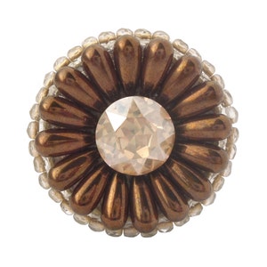 以下が含まれることがあります： 茶色と白のビーズでできた花のブローチ。中央には透明なラインストーンが埋め込まれています。